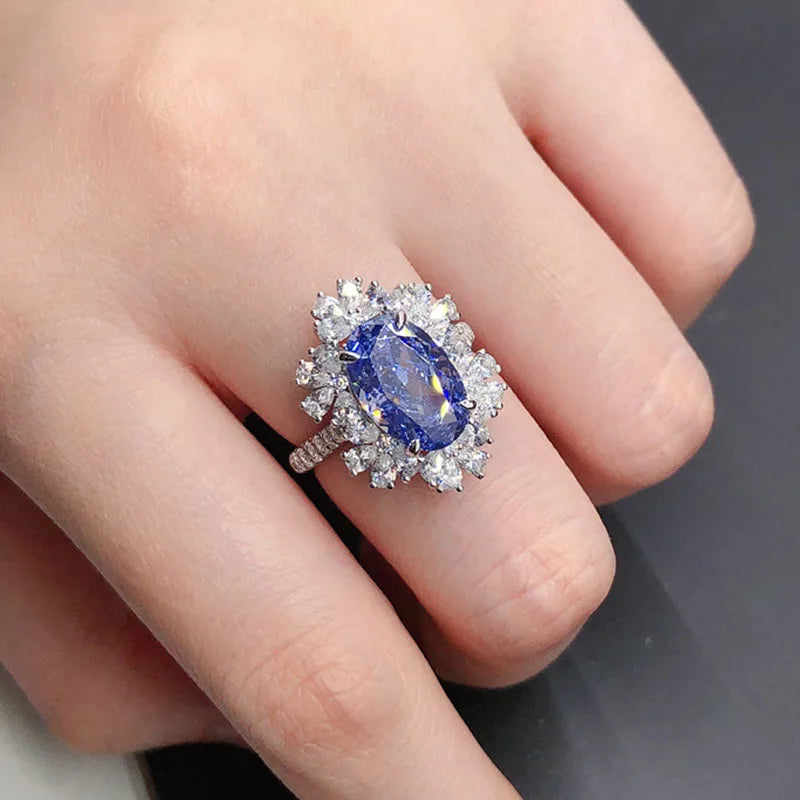 Ring with a blue gemstone and diamond accents on a finger against a neutral background