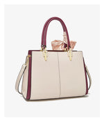 Beige handbag with purple accents and a pink bow on a white background