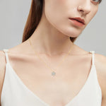 Woman wearing a gold necklace with a star-shaped pendant against a neutral background