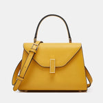 Yellow handbag with a gold buckle on a light gray background