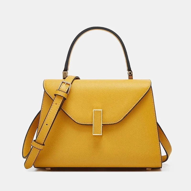 Yellow handbag with a gold buckle on a light gray background