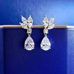 Pair of silver earrings with clear gemstones on a blue background