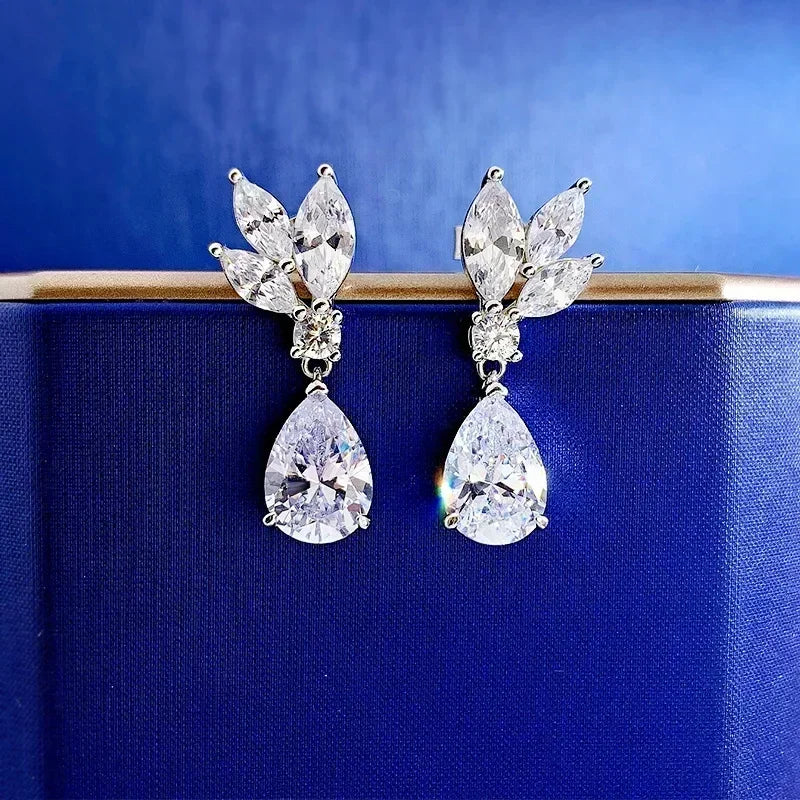 Pair of silver earrings with clear gemstones on a blue background