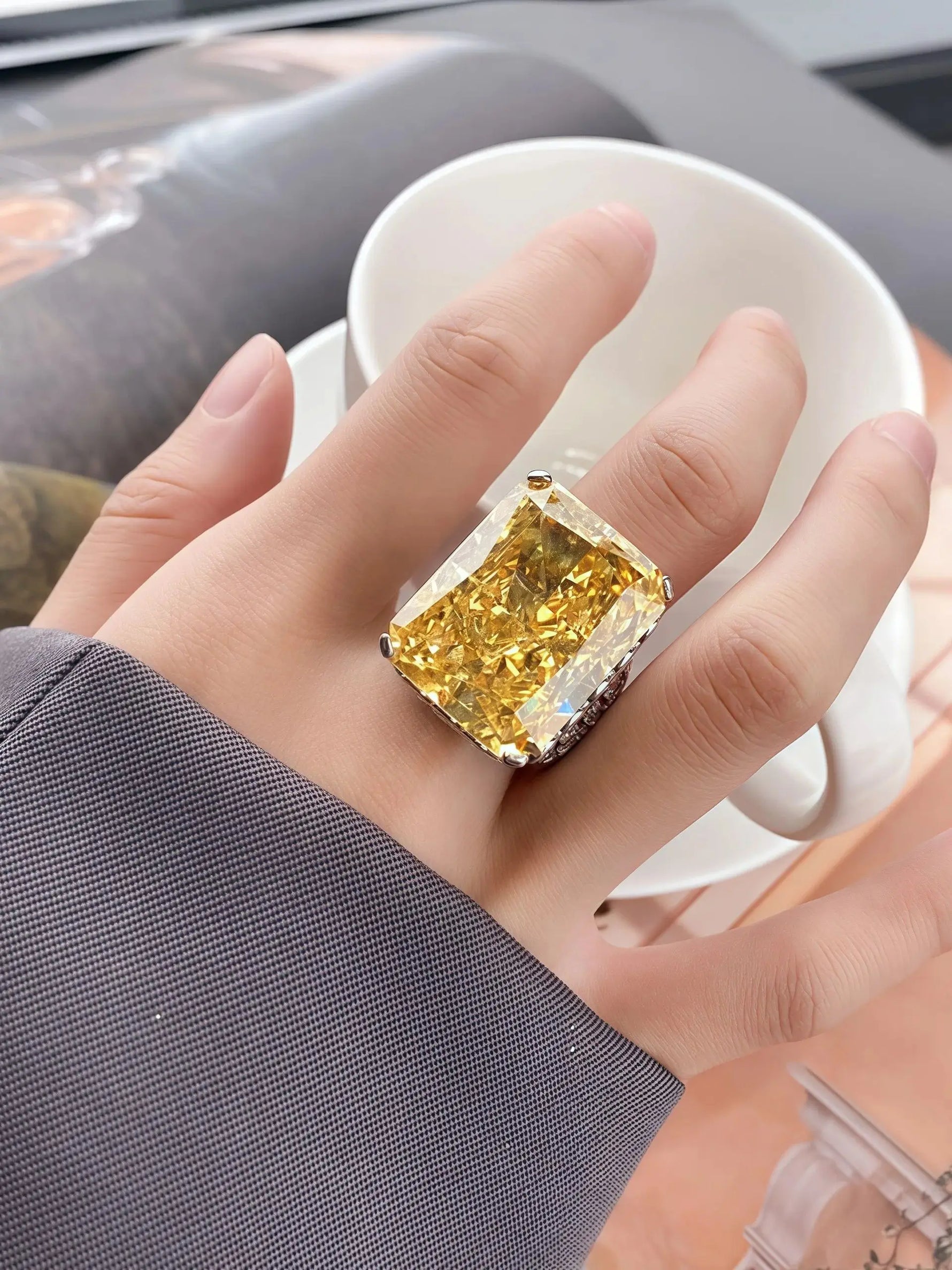 Gold ring with a large diamond on a finger, blurred background