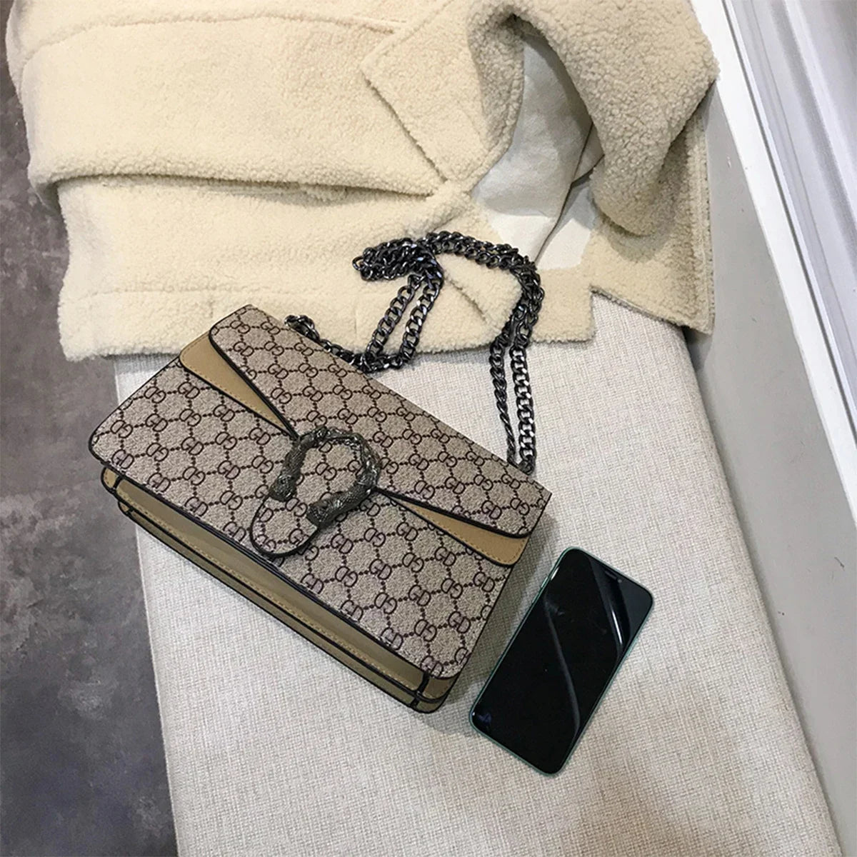 Designer handbag with chain strap on a textured surface
