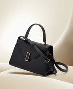 Black handbag with gold accents on a beige surface