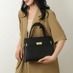 Woman holding a black handbag against a neutral background