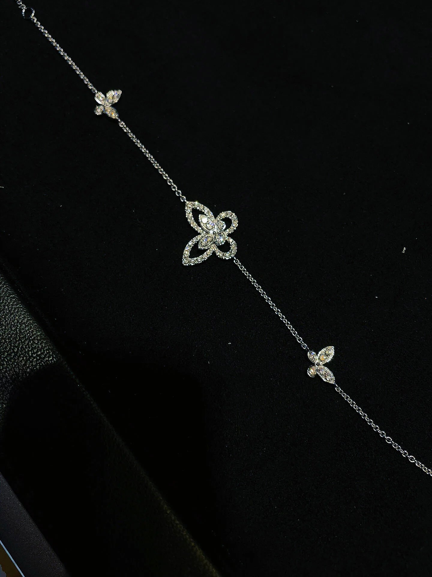 Delicate silver necklace with butterfly-shaped pendants on a black background