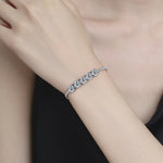 Silver bracelet on a person's wrist against a neutral background