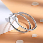 Silver hoop earrings on a soft peach background with white petals