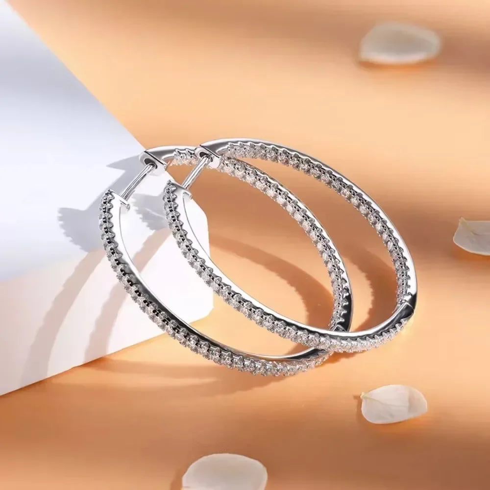 Silver hoop earrings on a soft peach background with white petals