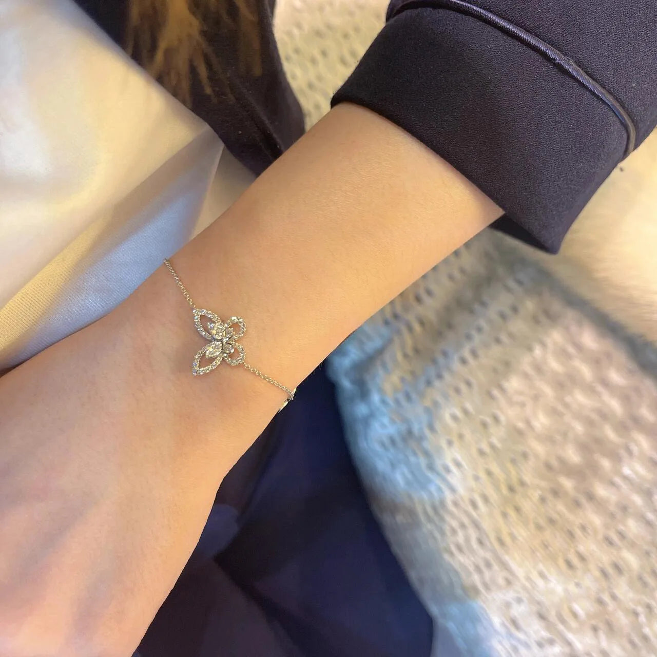 Silver butterfly bracelet on a wrist with a blurred background