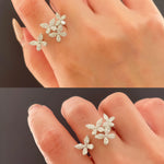 Silver leaf-shaped earrings being worn on a hand against a dark background