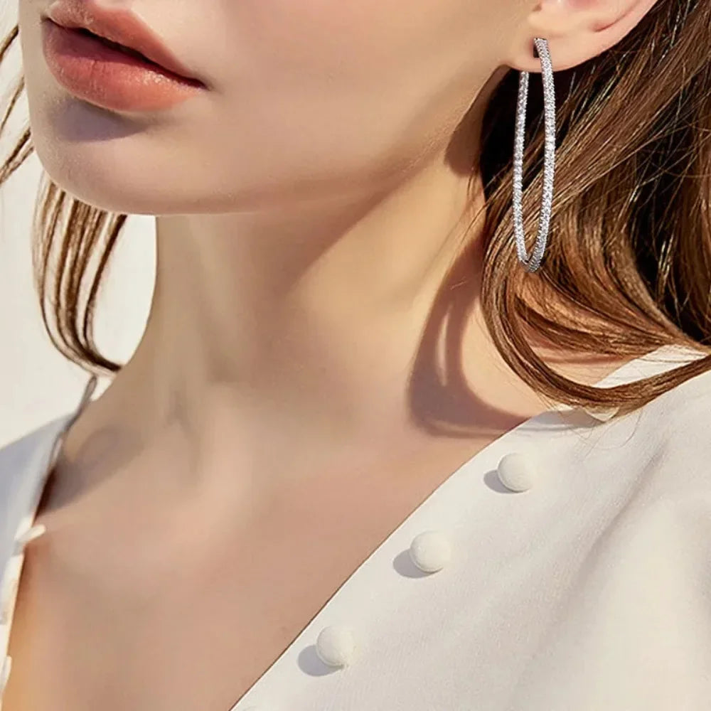 Close-up of a person wearing silver hoop earrings with a blurred background