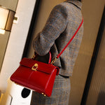 Person wearing a gray plaid coat holding a red handbag with a gold clasp.