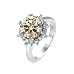 Silver ring with a large central diamond and smaller diamonds around on a white background