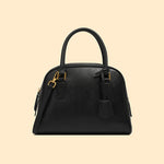 Black handbag with gold accents on a beige background