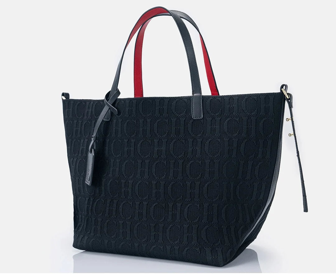 Black handbag with red and white accents on a light gray background