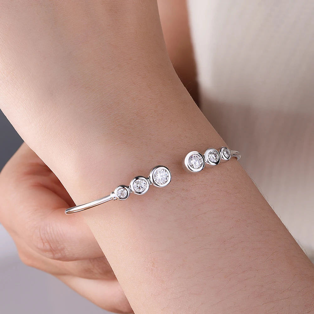 Silver bracelet with round diamonds on a wrist against a neutral background