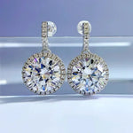 Pair of diamond earrings on a reflective surface with a gradient background
