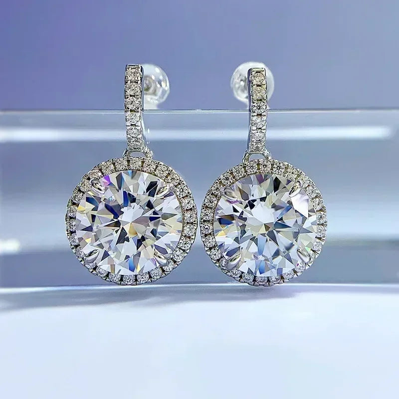 Pair of diamond earrings on a reflective surface with a gradient background