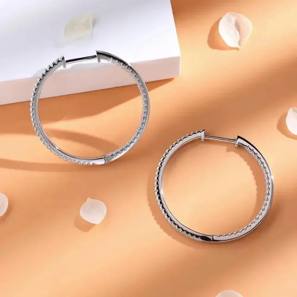 Silver hoop earrings on a peach-colored surface with white petals.