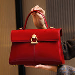Red handbag with gold accents held by a person against a neutral background