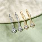 Three pairs of diamond earrings in silver, gold, and rose gold on a light background.