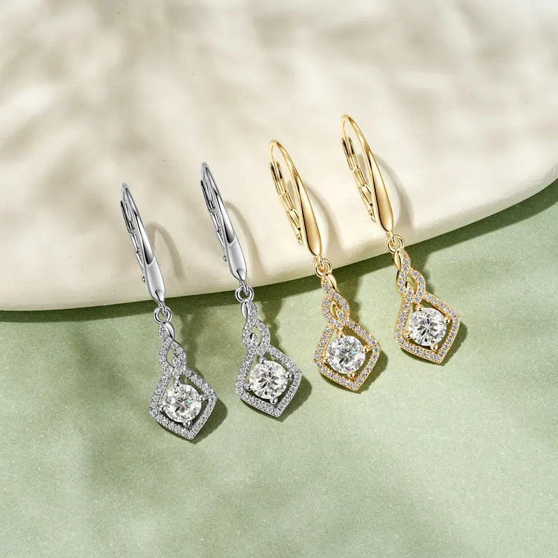 Three pairs of diamond earrings in silver, gold, and rose gold on a light background.