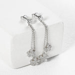 Silver floral earrings on a white cushion