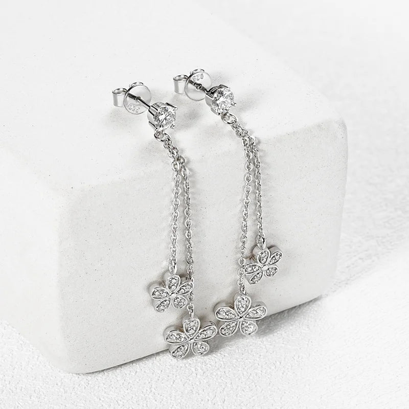 Silver floral earrings on a white cushion