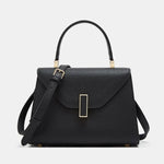 Black handbag with a gold clasp on a light gray background