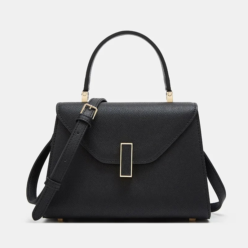 Black handbag with a gold clasp on a light gray background
