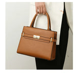 Brown handbag held by a person against a neutral background