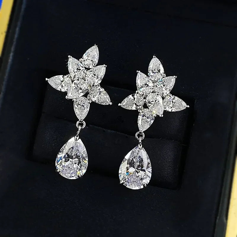 Pair of silver earrings with floral and teardrop designs on a black background