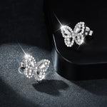 Butterfly-shaped earrings with sparkling stones on a dark surface