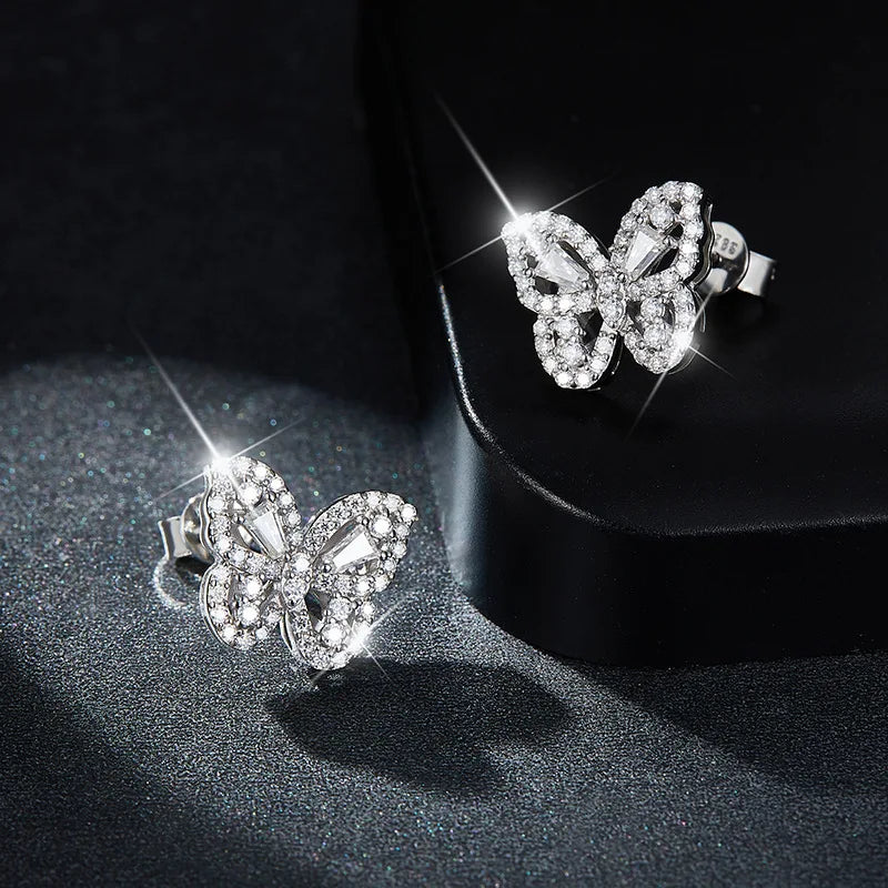 Butterfly-shaped earrings with sparkling stones on a dark surface