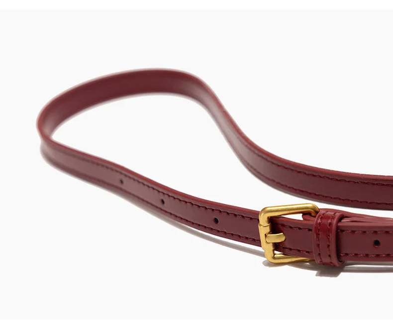 Red leather belt with a gold buckle on a white background