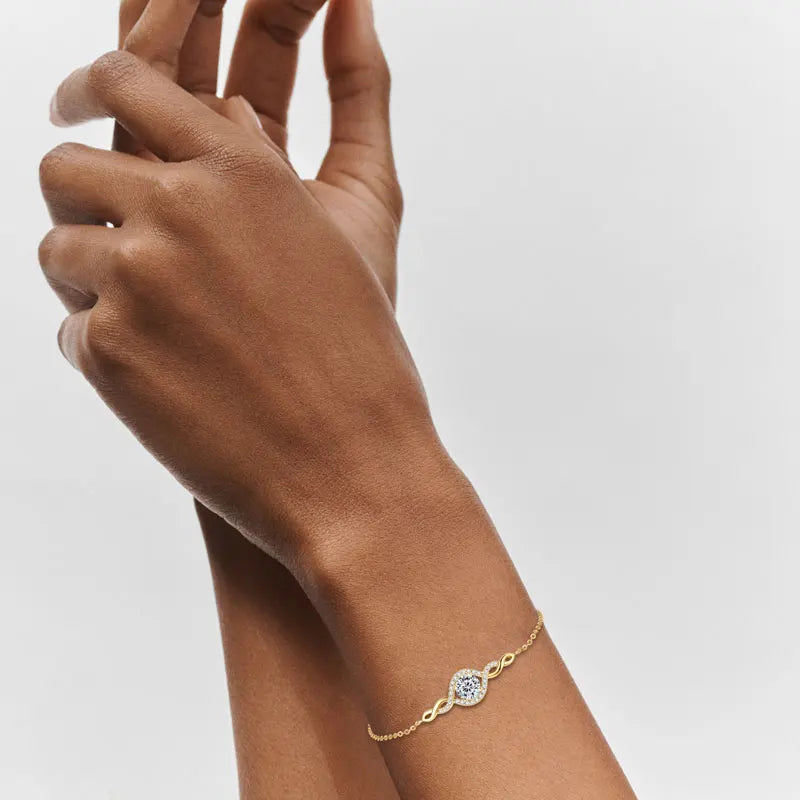 Gold bracelet with a diamond on a wrist against a light gray background