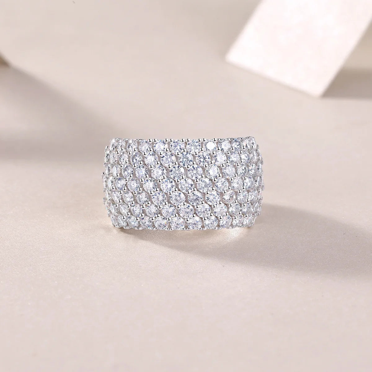Silver ring with multiple rows of diamonds on a beige background