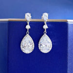 Teardrop-shaped diamond earrings on a blue background