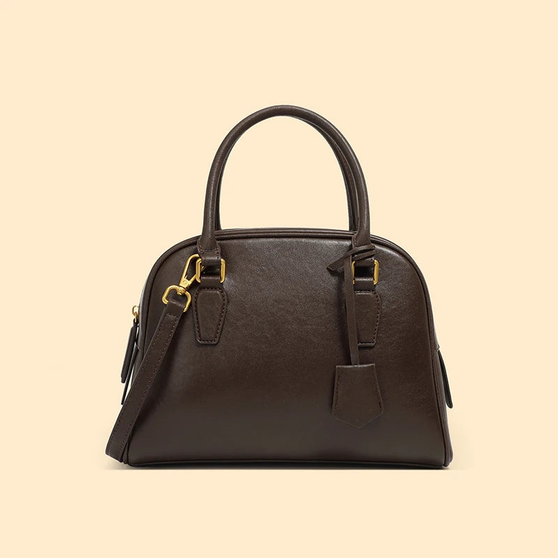 Brown handbag with gold hardware on a beige background
