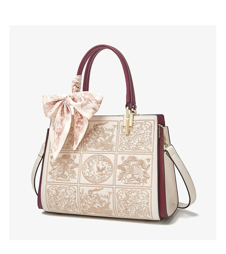 Designer handbag with intricate patterns and a decorative bow on a white background