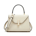Beige handbag with black handle and strap on a white background