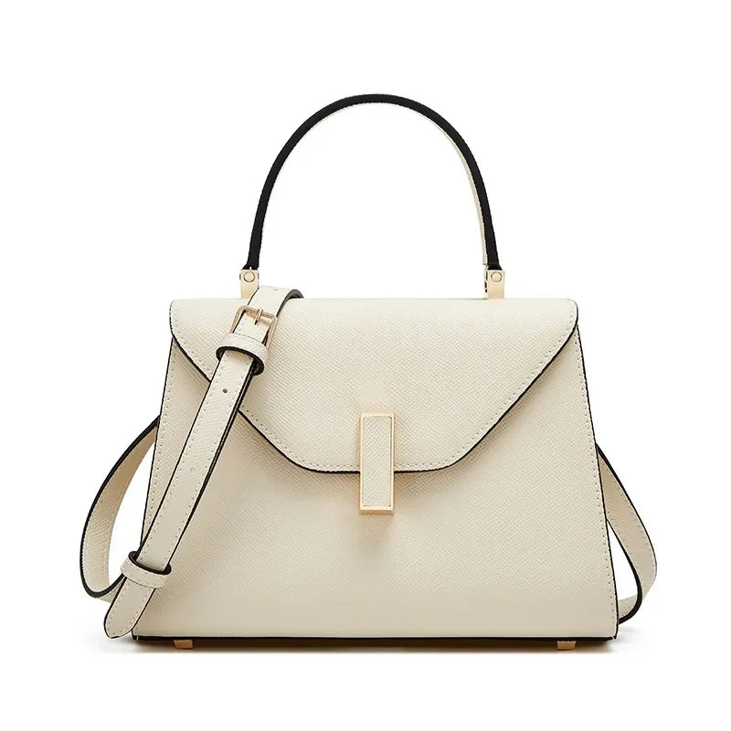 Beige handbag with black handle and strap on a white background