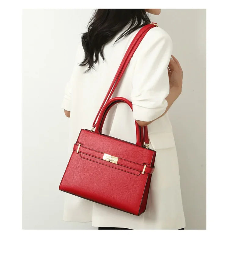Red handbag held by a person against a neutral background