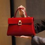 Red handbag held by a person against a neutral background
