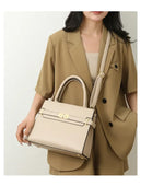 Woman holding a beige handbag wearing a matching beige suit against a white background