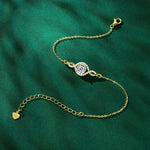 Gold bracelet with a heart charm on a green fabric background