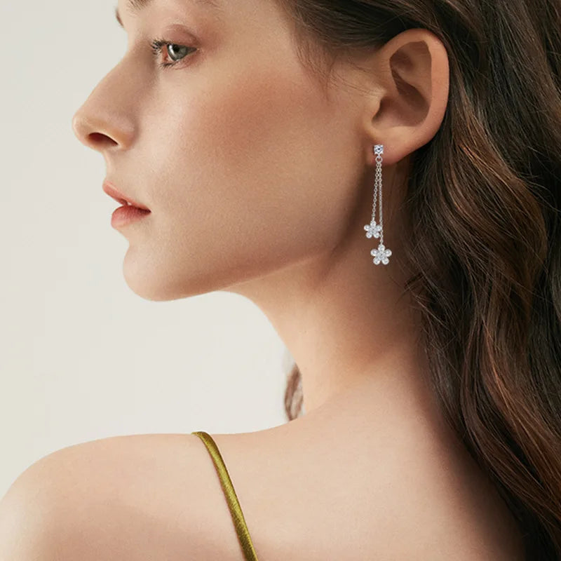 Close-up of a woman wearing a floral earring with a plain background